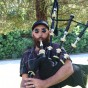 Miles Sweet holds the bagpipes and plays.